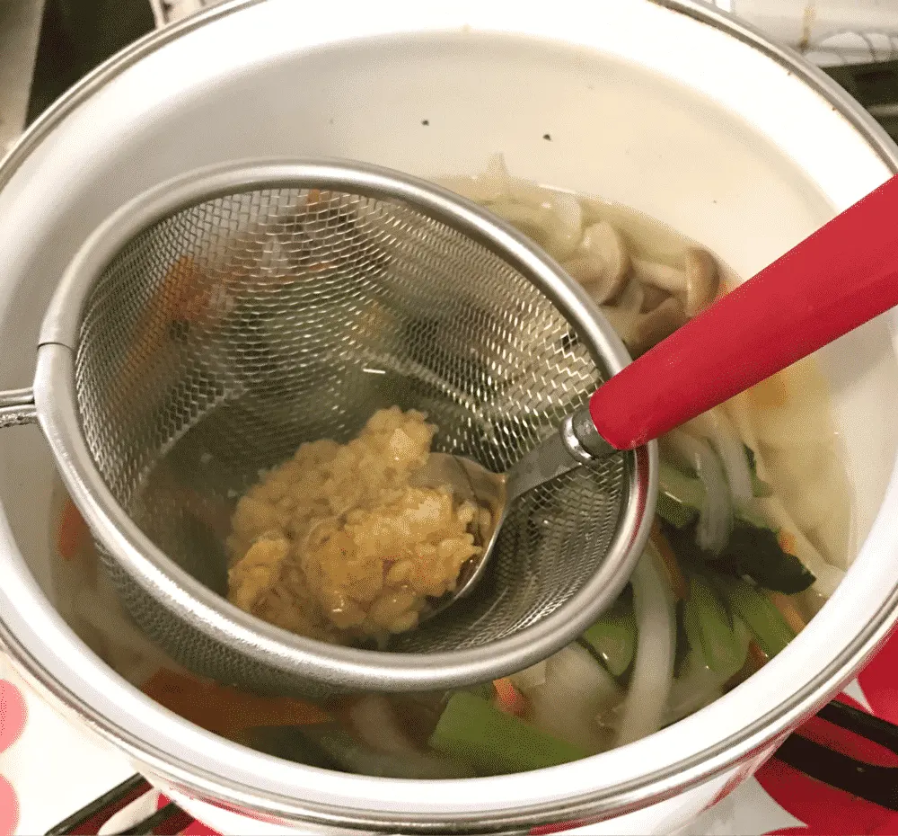 スプーンでみそを鍋に溶かし入れて味噌汁の完成